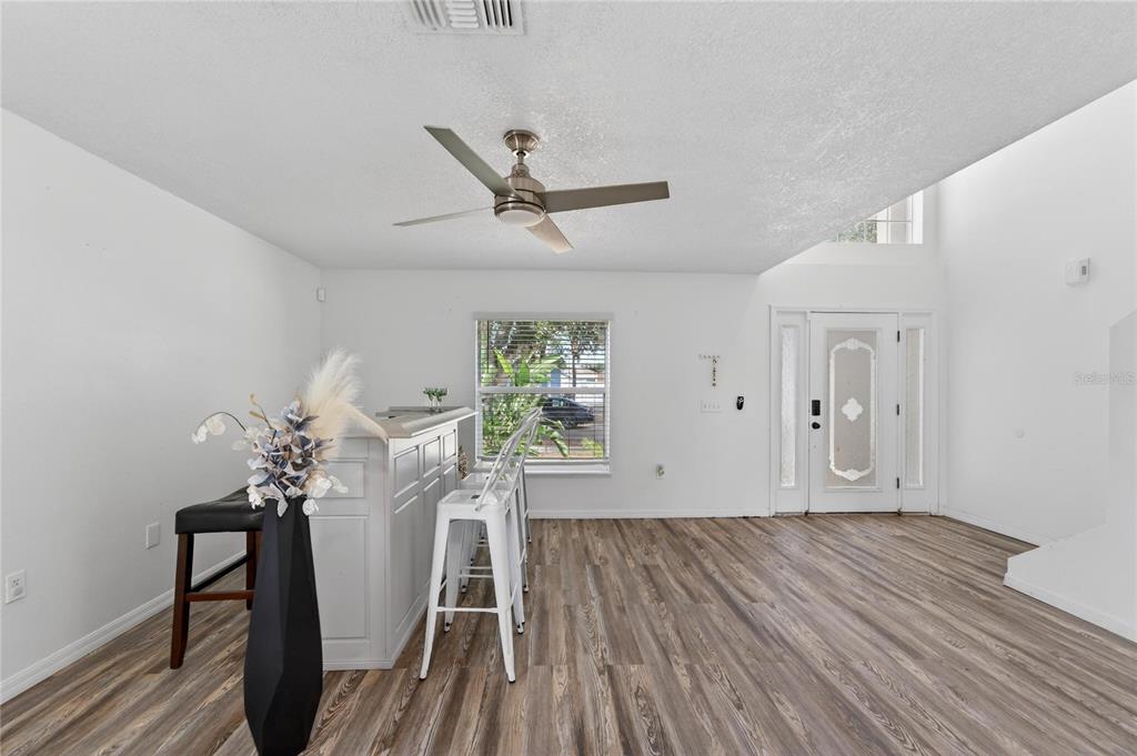 A room with wood-look flooring, a kitchen island with bar stools, and a front door — 10325 FROG POND DRIVE, RIVERVIEW, FL
