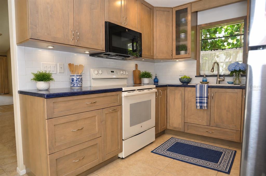 A kitchen features wood cabinets, white subway tile backsplashes, a white stove, and blue countertops — 5565 SALEM SQUARE DRIVE N, PALM HARBOR, FL