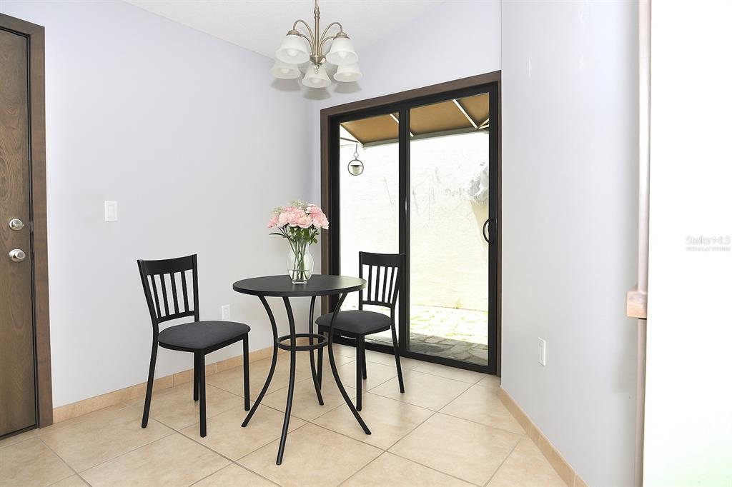 A dining area features a small round table, two chairs, tile flooring, and sliding glass doors — 5565 SALEM SQUARE DRIVE N, PALM HARBOR, FL