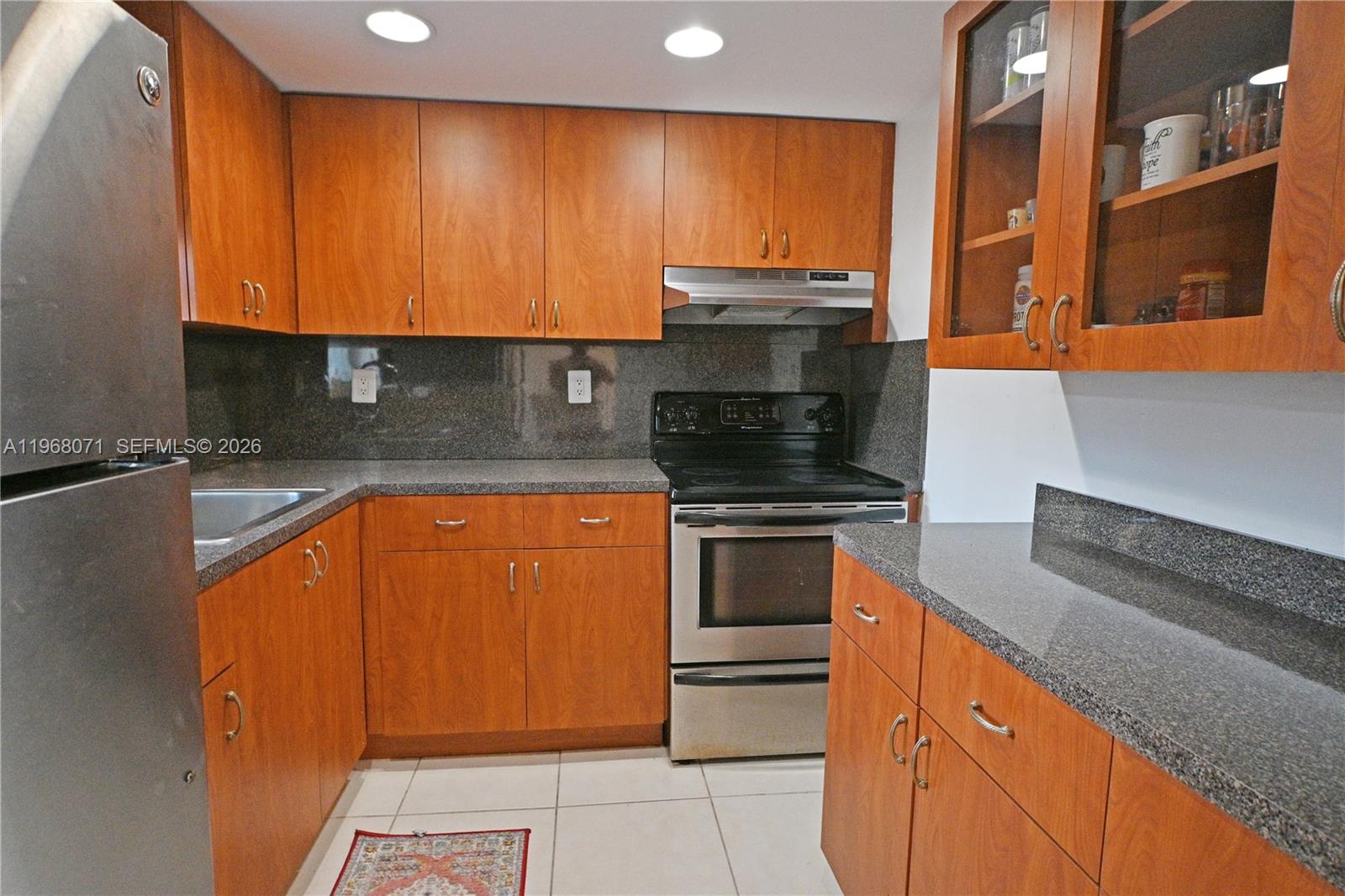 A kitchen features wood cabinets, granite countertops, and stainless steel appliances — 947 Lenox Ave # 203, Miami Beach FL 33139, MIAMI BEACH, FL