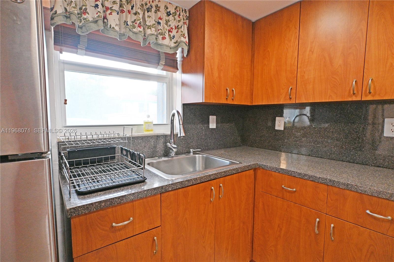 A kitchen features wood cabinets, granite countertops, a stainless steel sink, and a window — 947 Lenox Ave # 203, Miami Beach FL 33139, MIAMI BEACH, FL