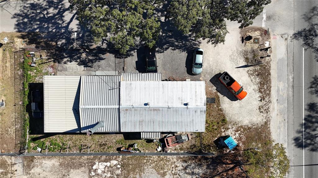 An aerial view shows a metal-roofed building with several vehicles parked on the surrounding lot — 10 BARRY AVENUE, MASCOTTE, FL