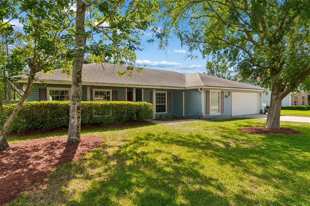 A single-story house with blue siding, a white garage door, and a front lawn — 12160 BANYAN TREE DRIVE, JACKSONVILLE, FL