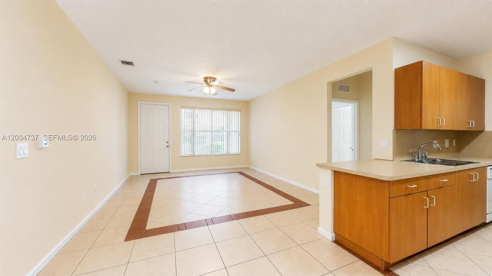 An open-concept kitchen and dining area features light tile flooring and wood-toned cabinetry — 3557 Forest Hill Blvd # 51, Palm Springs FL 33406, PALM SPRINGS, FL