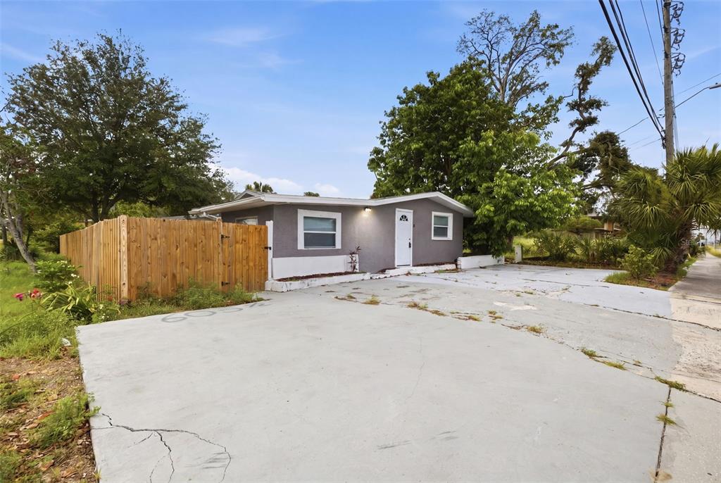 A gray, single-story house features a large concrete driveway and a wooden privacy fence — 605 S S DISSTON AVE, TARPON SPRINGS, FL