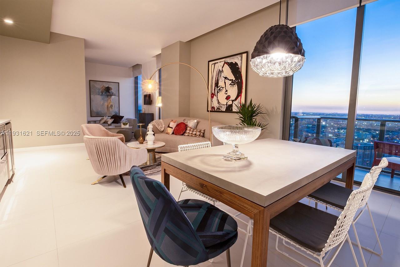 A modern dining and living area features a concrete table, patterned chairs, and floor-to-ceiling windows — 501 NE 31st St, Miami FL 33137, MIAMI, FL