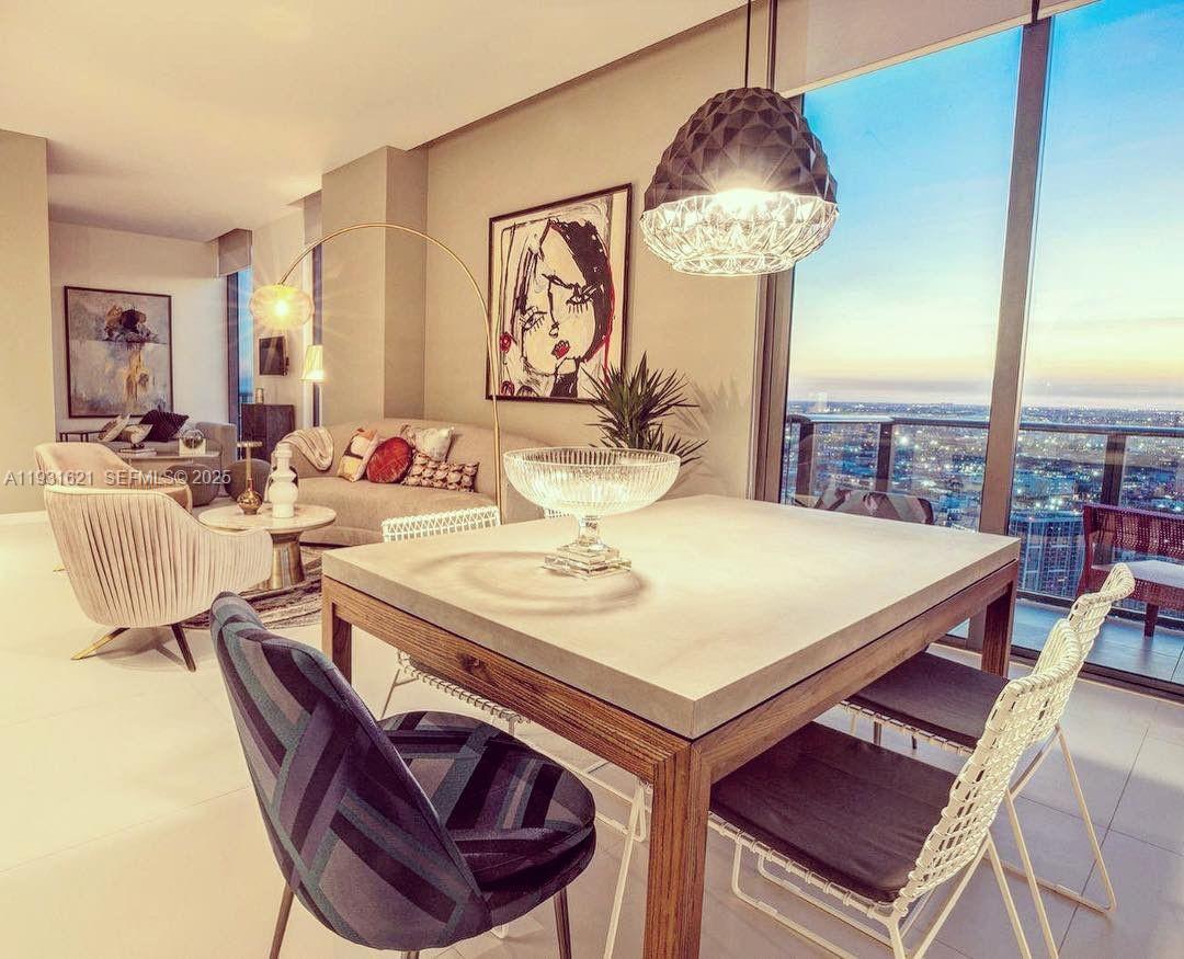 A modern dining area features a concrete-topped table, patterned chairs, and floor-to-ceiling city views — 501 NE 31st St, Miami FL 33137, MIAMI, FL