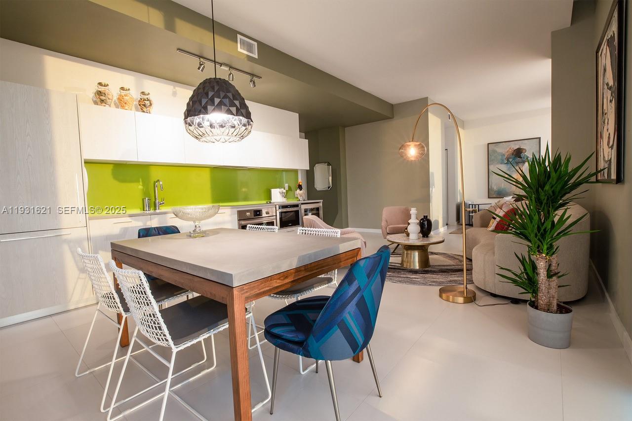 An open-concept kitchen and living area features a concrete dining table and lime green backsplash — 501 NE 31st St, Miami FL 33137, MIAMI, FL