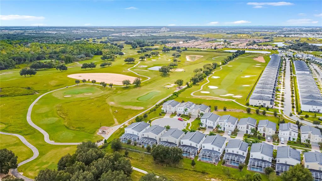 An aerial view shows a residential neighborhood bordering a large golf course with sand traps — 8809 CRUDEN BAY COURT, DAVENPORT, FL