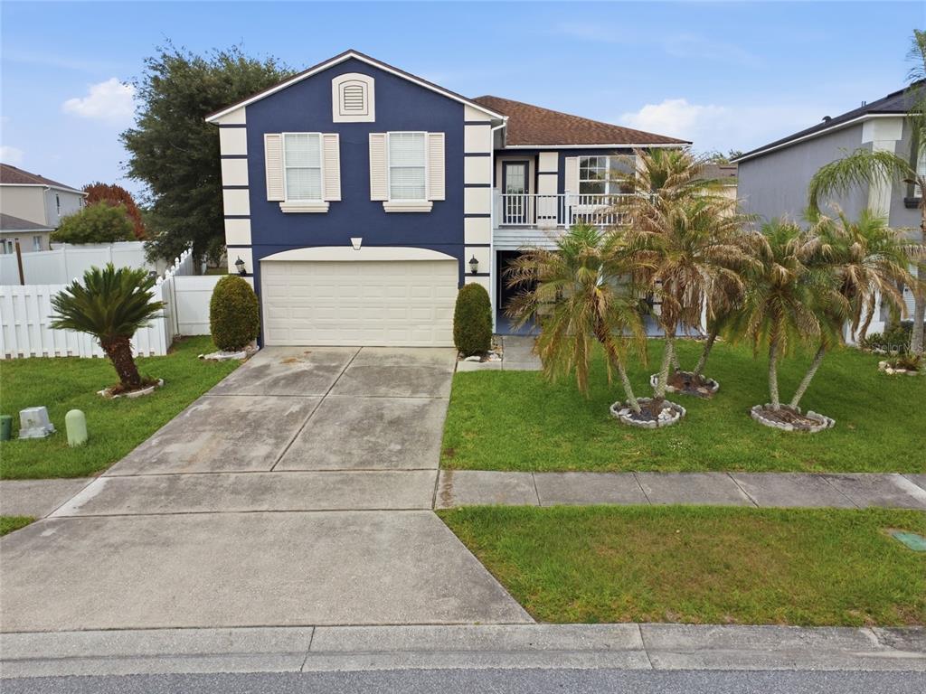 A two-story house with a blue exterior, a two-car garage, and palm trees in front — 1161 KEMPTON CHASE PARKWAY, ORLANDO, FL