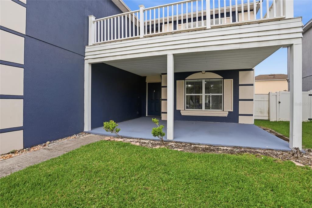 A covered patio area features a dark blue exterior wall, a window, and a balcony above — 1161 KEMPTON CHASE PARKWAY, ORLANDO, FL
