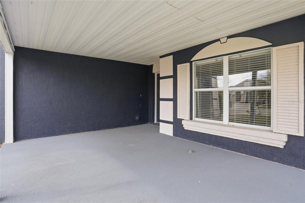 A covered porch with a gray concrete floor, dark blue walls, and a white-trimmed window — 1161 KEMPTON CHASE PARKWAY, ORLANDO, FL