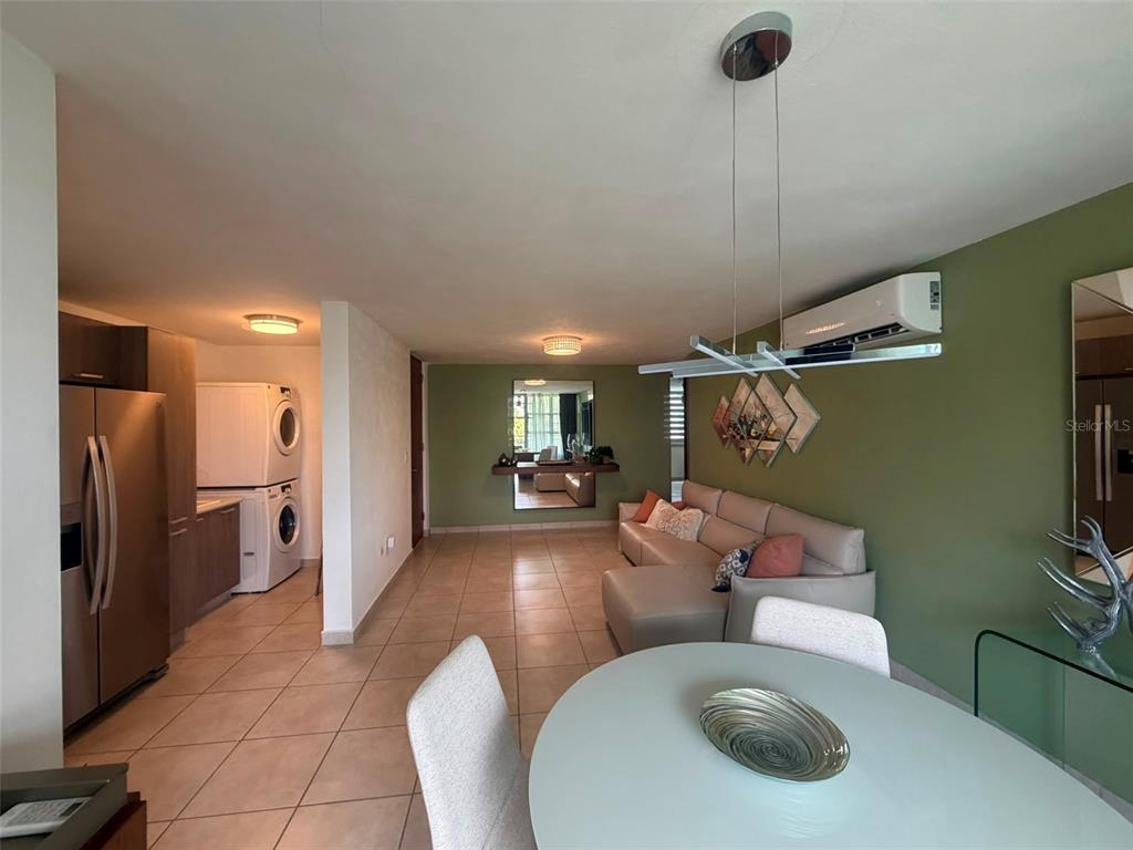 A living room and kitchen area features tile floors, a sectional sofa, and stacked laundry — CAMINITO ALTO CARR 189, GURABO, PR