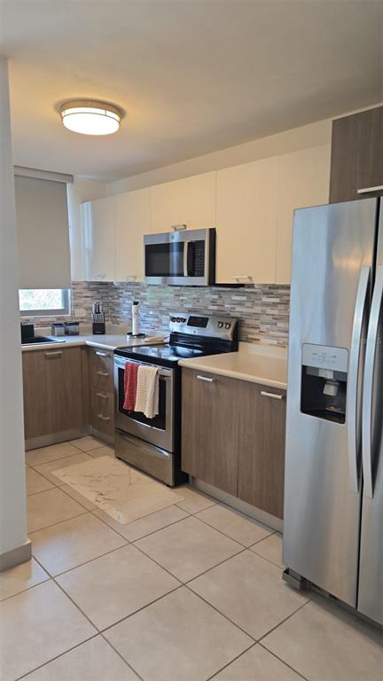 A kitchen features light wood cabinets, stainless steel appliances, a tiled backsplash, and light flooring — CAMINITO ALTO CARR 189, GURABO, PR