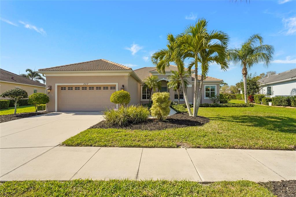 A single-story house with a tan stucco exterior, a two-car garage, and palm trees — 357 MARSH CREEK ROAD, VENICE, FL