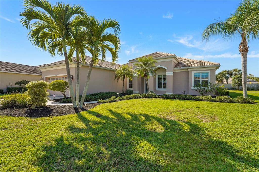 A single-story suburban house with a tan stucco exterior, tile roof, and palm trees — 357 MARSH CREEK ROAD, VENICE, FL