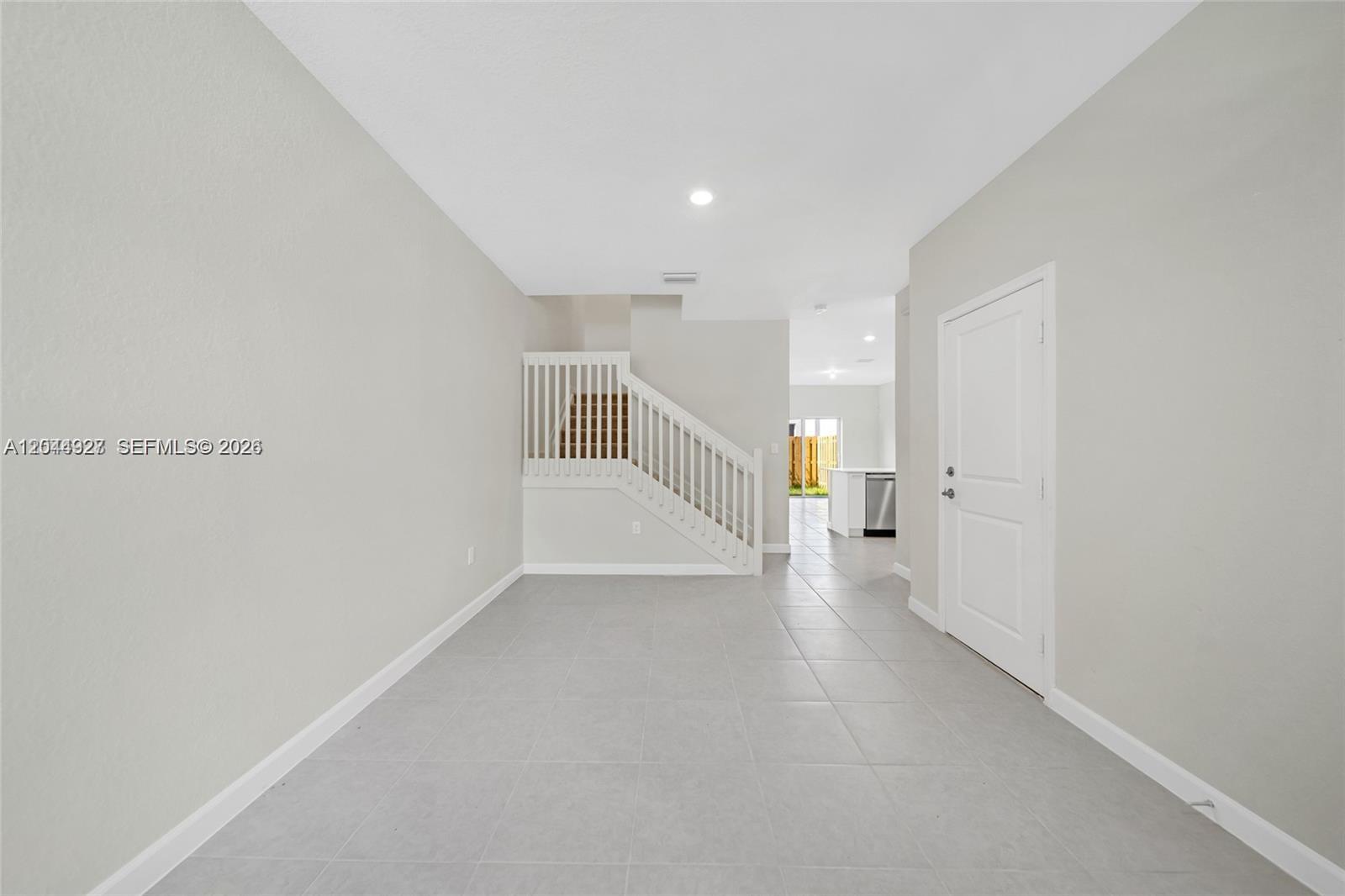 An interior view shows a tiled room with a staircase, white walls, and a door — 12942 NW 23rd Pl, Miami FL 33167, MIAMI, FL