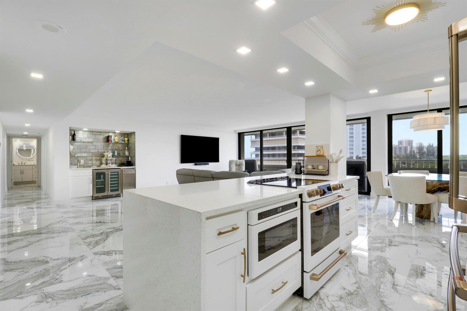 A modern kitchen with a white island, marble floors, and an open-concept living area — 5280 N Ocean Drive # 2f, Riviera Beach FL 33404, RIVIERA BEACH, FL