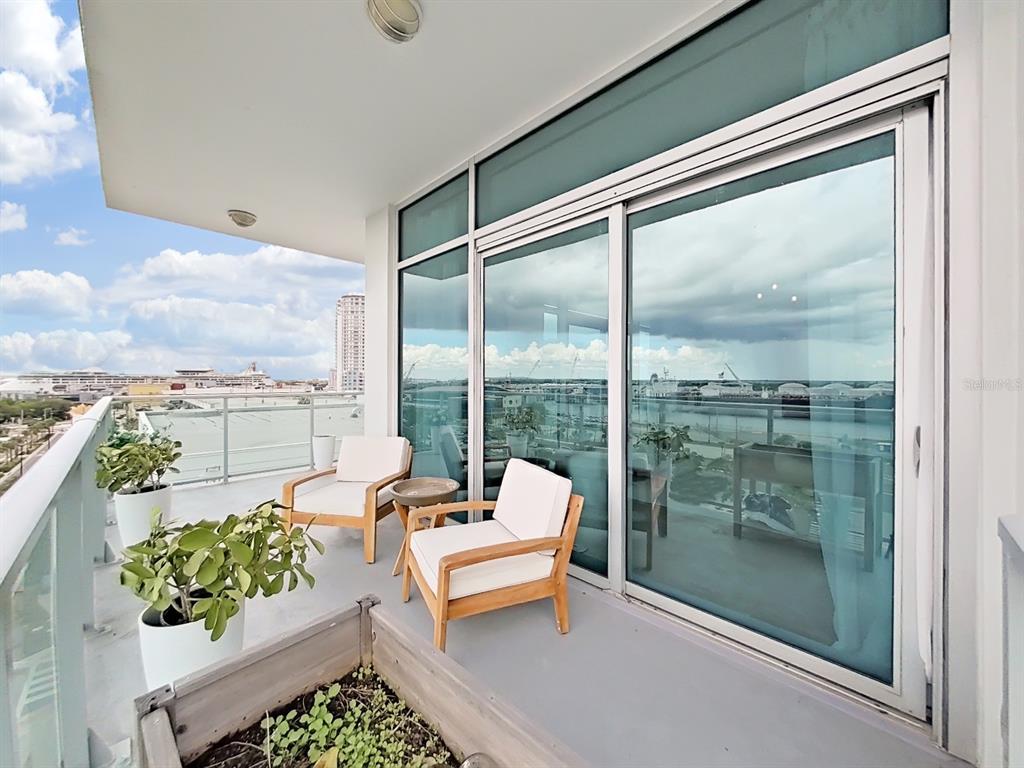 A balcony with two wooden chairs, potted plants, and a view of the harbor — 912 CHANNELSIDE DRIVE UNIT 2805, TAMPA, FL