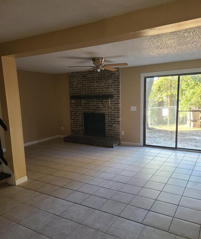 A living room with tile flooring, a brick fireplace, and sliding glass doors to the yard — 4910 SILVER OAKS VILLAGE UNIT B, ORLANDO, FL
