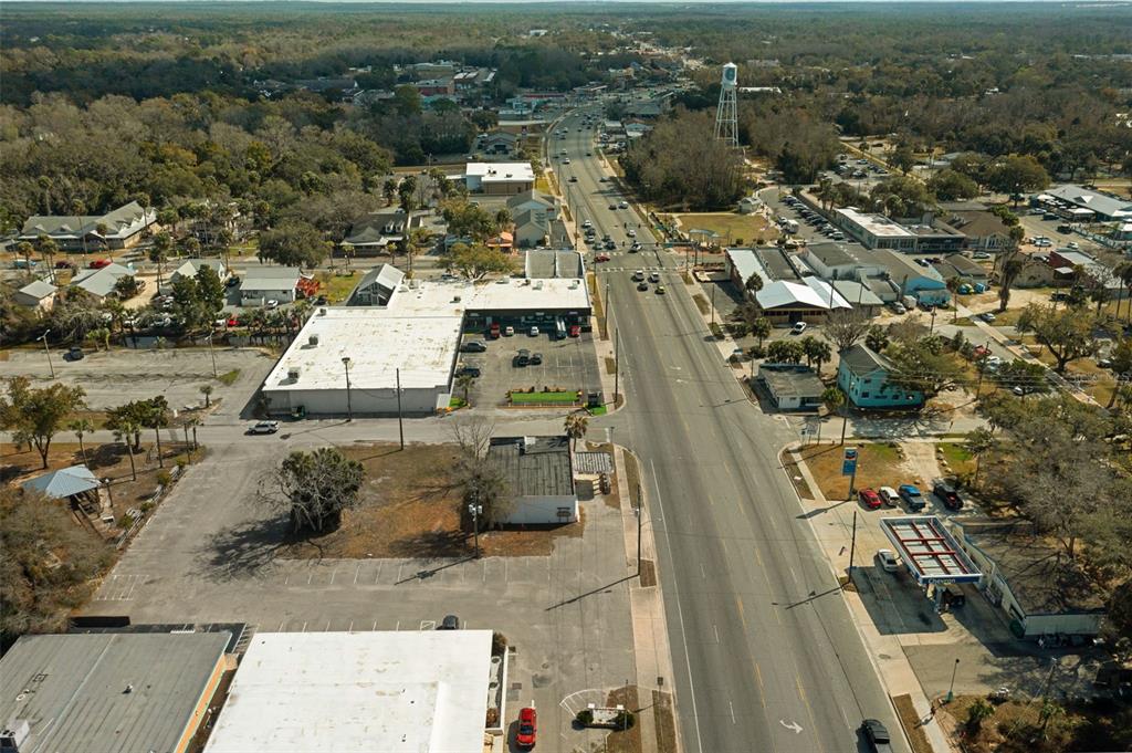 An aerial view shows a commercial street with buildings, parking lots, and a water tower — 103 NW US HIGHWAY 19, CRYSTAL RIVER, FL