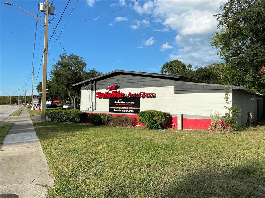 A Safelite AutoGlass building with a red and white exterior sits on a grassy lot — 2525 N MAIN STREET, GAINESVILLE, FL