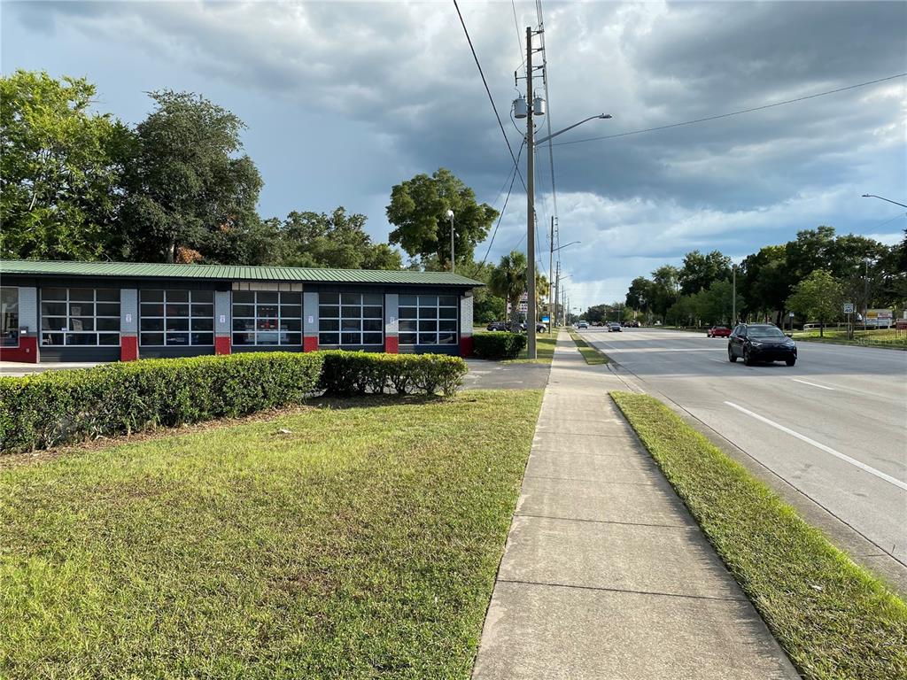 A commercial building with a green roof and multiple garage doors sits beside a sidewalk — 2525 N MAIN STREET, GAINESVILLE, FL