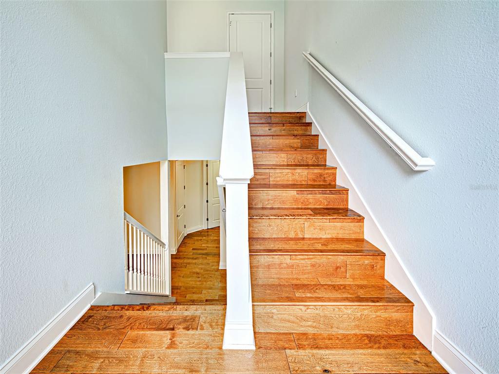 A staircase with wood treads and white railings leads to an upper landing and door — 445 NOKOMIS AVENUE S UNIT 210, VENICE, FL