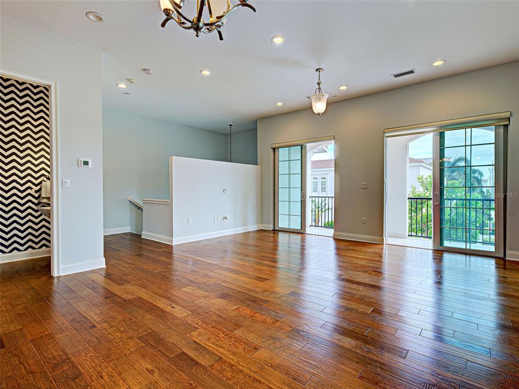 A living room with hardwood floors, recessed lighting, and two sliding glass doors to balconies — 445 NOKOMIS AVENUE S UNIT 210, VENICE, FL