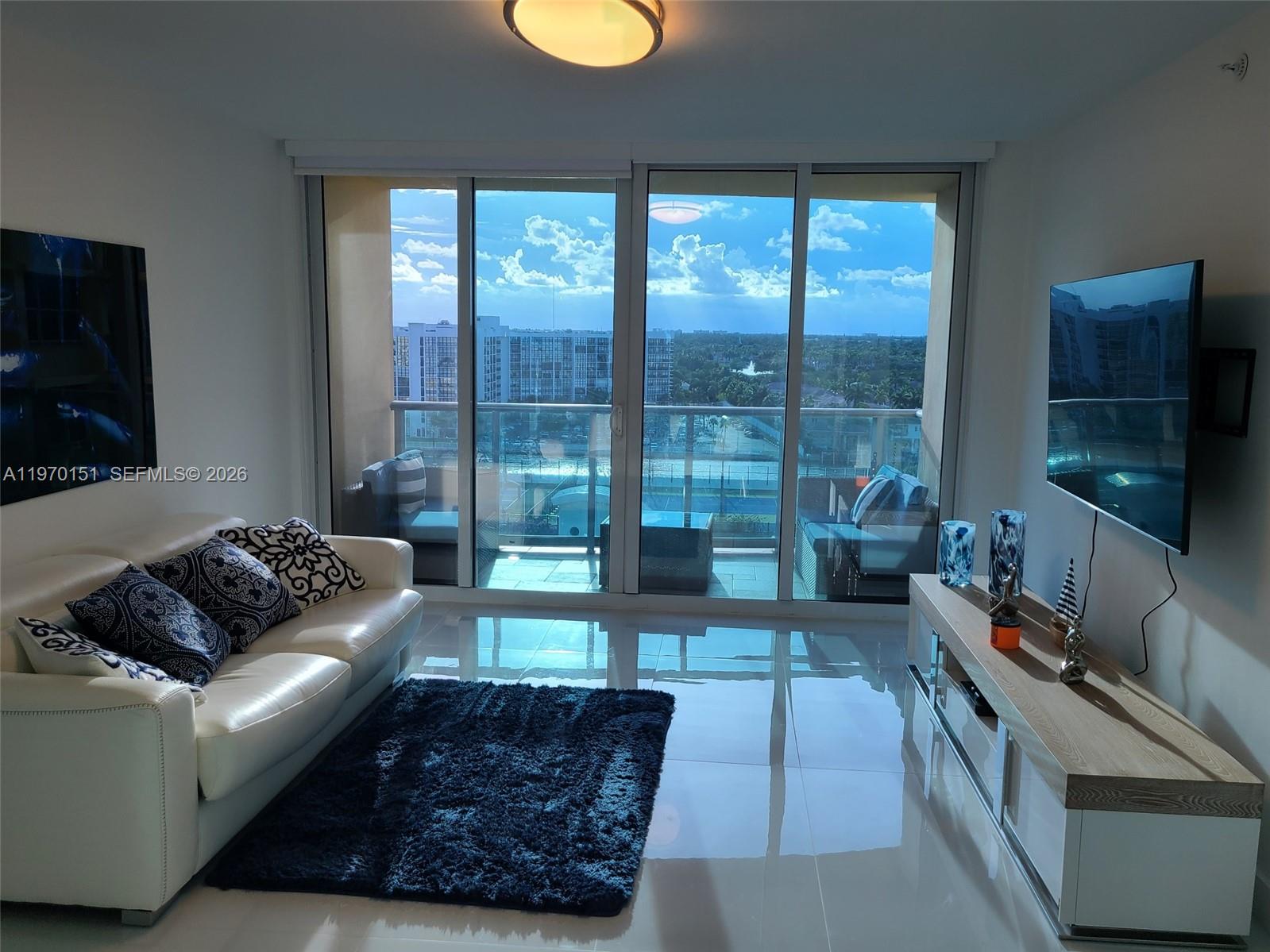 A living room features a white sofa, a dark rug, and a balcony with views — 2501 S Ocean Dr # 1031, Hollywood FL 33019, HOLLYWOOD, FL