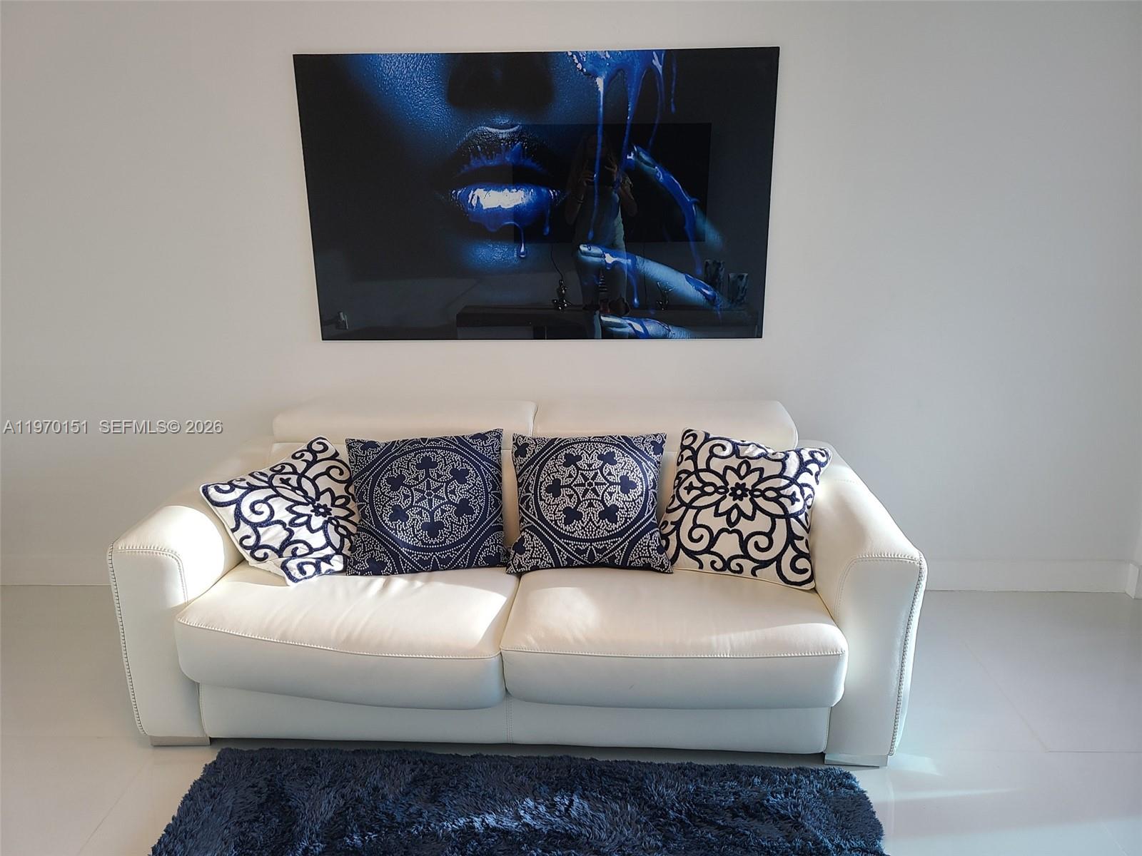 A white leather sofa with patterned blue pillows sits beneath a large blue artwork — 2501 S Ocean Dr # 1031, Hollywood FL 33019, HOLLYWOOD, FL