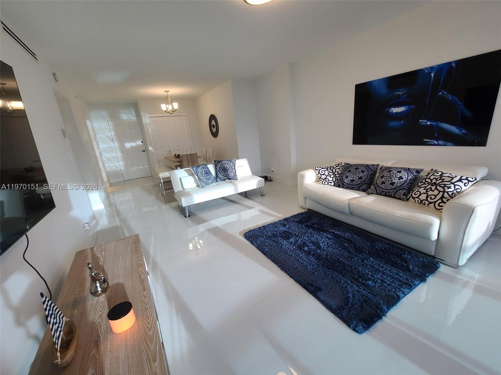 A modern living room features white tile floors, a white sofa, and a blue rug — 2501 S Ocean Dr # 1031, Hollywood FL 33019, HOLLYWOOD, FL