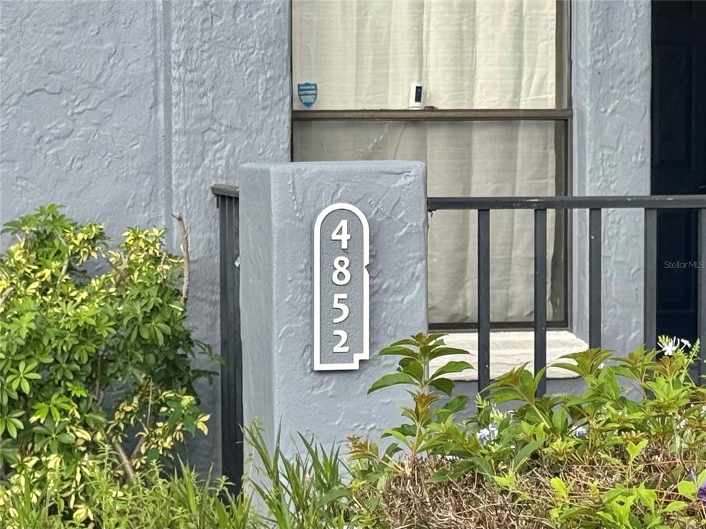 A house number plaque with the digits 4852 is mounted on a gray stucco pillar — 4852 MARKS TERRACE UNIT 52, ORLANDO, FL
