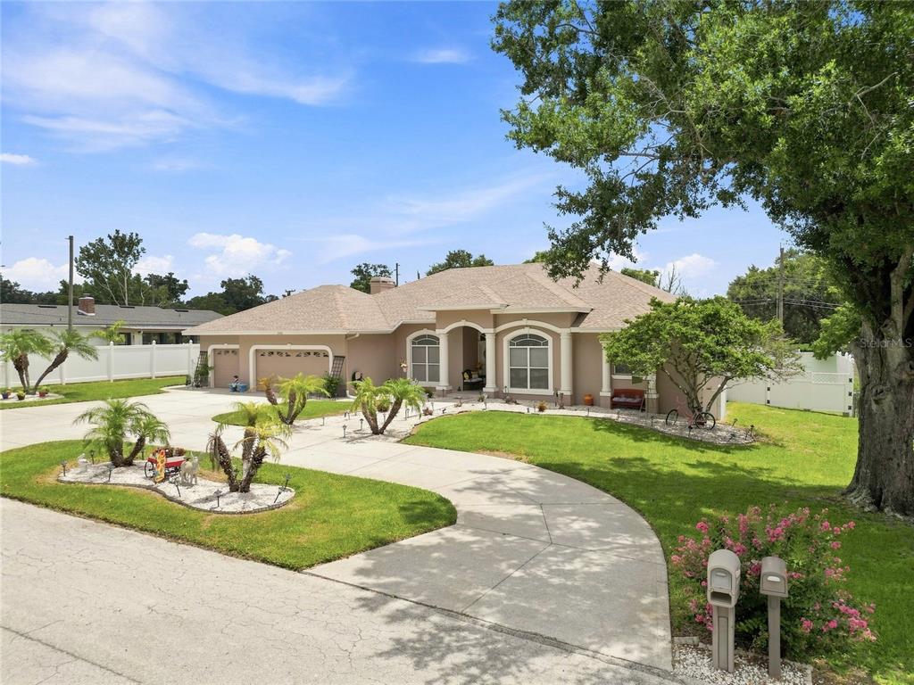 A single-story house with a beige stucco exterior, a multi-car garage, and a curved driveway — 5008 LAKEVIEW BOULEVARD, LAKELAND, FL