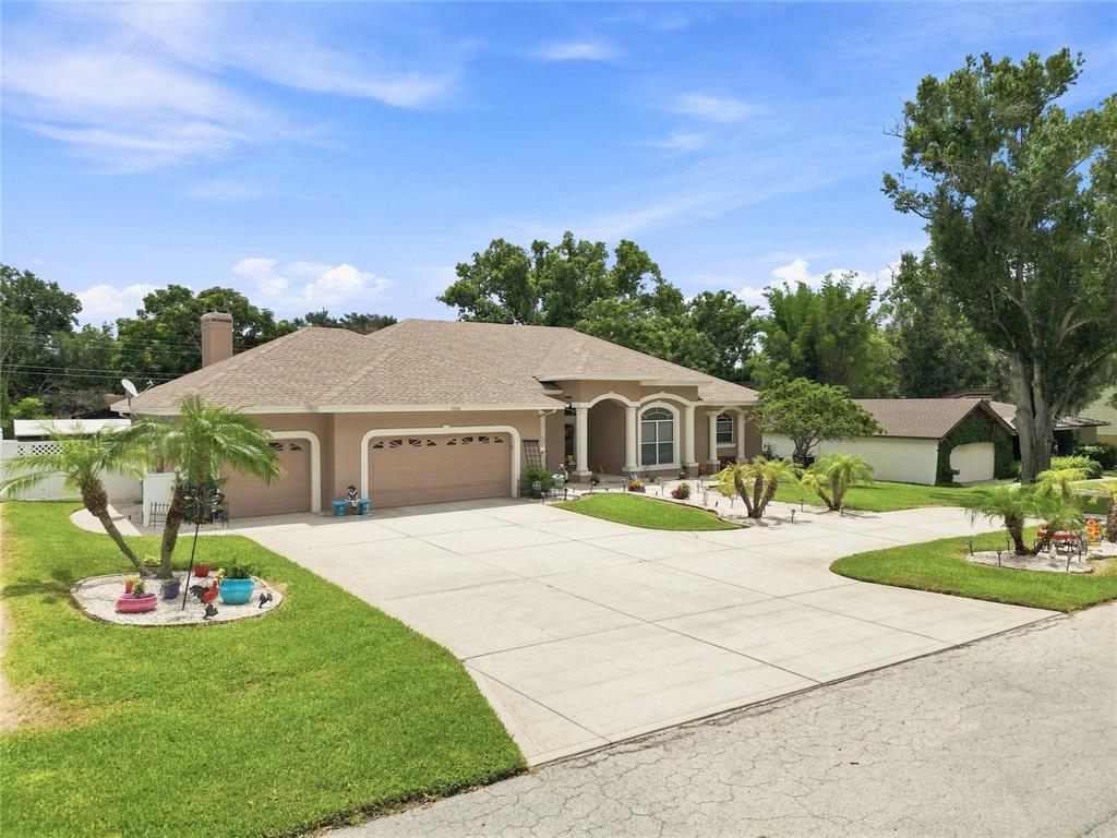 A tan single-story house with a large concrete driveway and a three-car garage — 5008 LAKEVIEW BOULEVARD, LAKELAND, FL