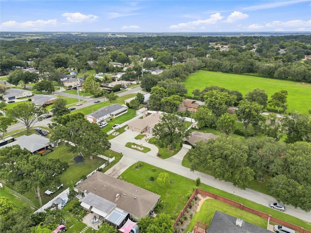 An aerial view shows several houses surrounded by trees, lawns, and a large open field — 5008 LAKEVIEW BOULEVARD, LAKELAND, FL