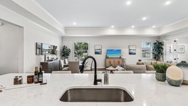 A kitchen island with a sink overlooks an open-concept living and dining area — 30653 PRESTWICK AVENUE, SORRENTO, FL