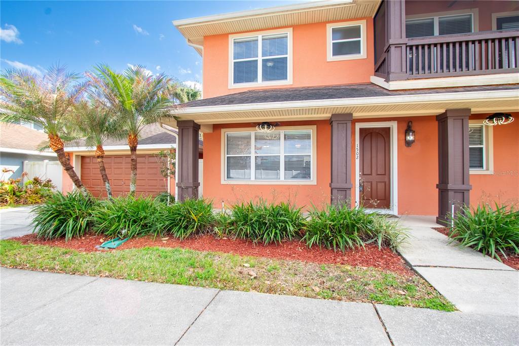 A two-story orange house features a brown front door, dark columns, and a landscaped yard — 1502 PAGE AVENUE, ORLANDO, FL