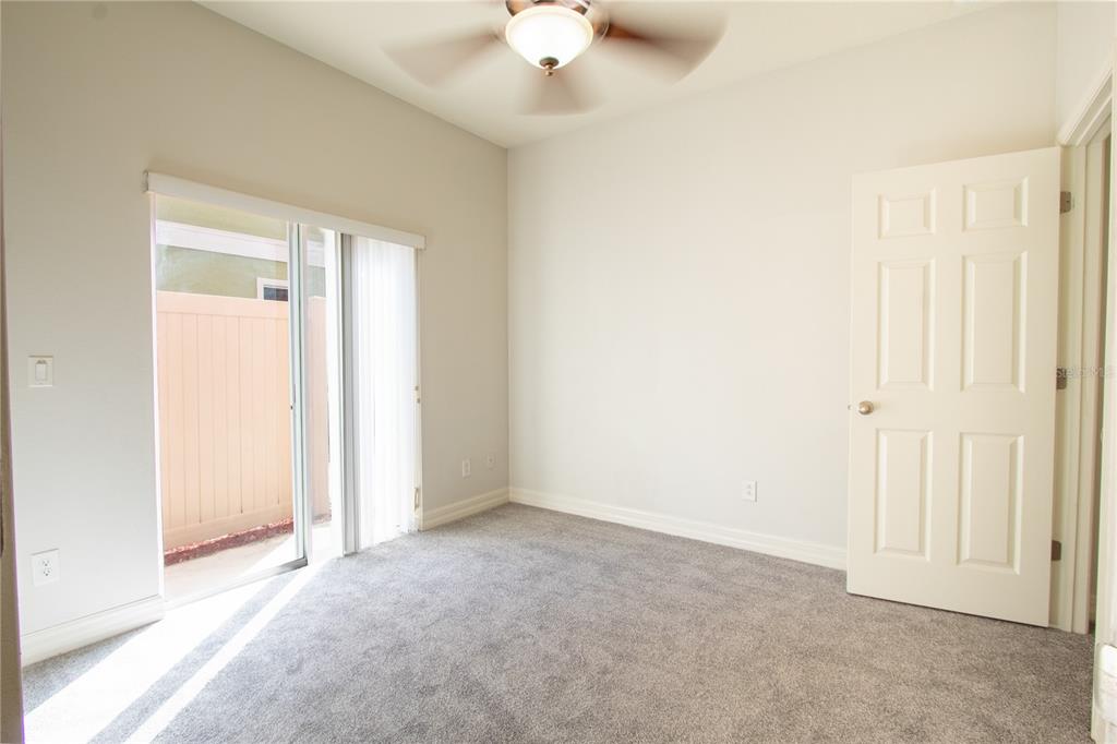 A bedroom with gray carpet, a ceiling fan, a white door, and a sliding glass door — 1502 PAGE AVENUE, ORLANDO, FL