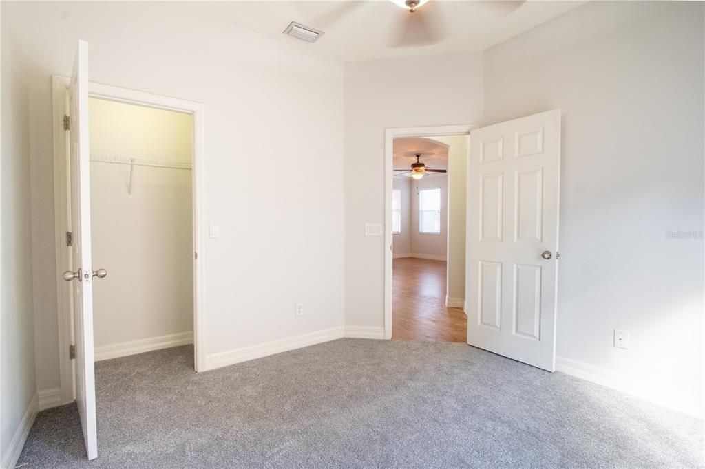 A bedroom with gray carpet, white walls, a closet, and an open doorway to another room — 1502 PAGE AVENUE, ORLANDO, FL