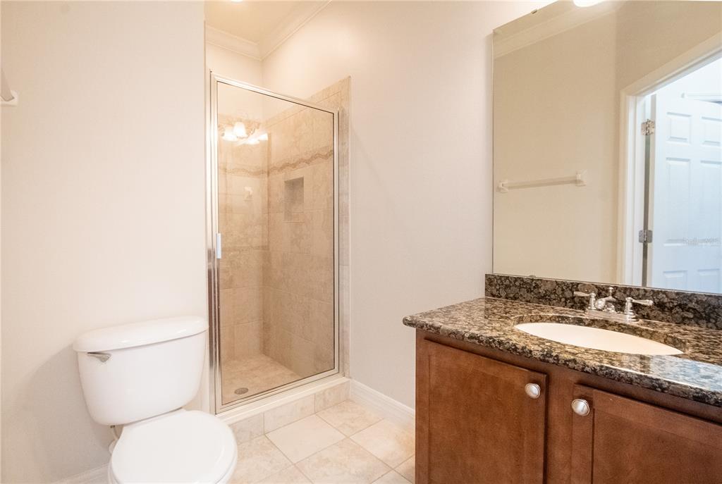 A bathroom features a glass-enclosed shower, a granite-topped vanity, and a white toilet — 1502 PAGE AVENUE, ORLANDO, FL