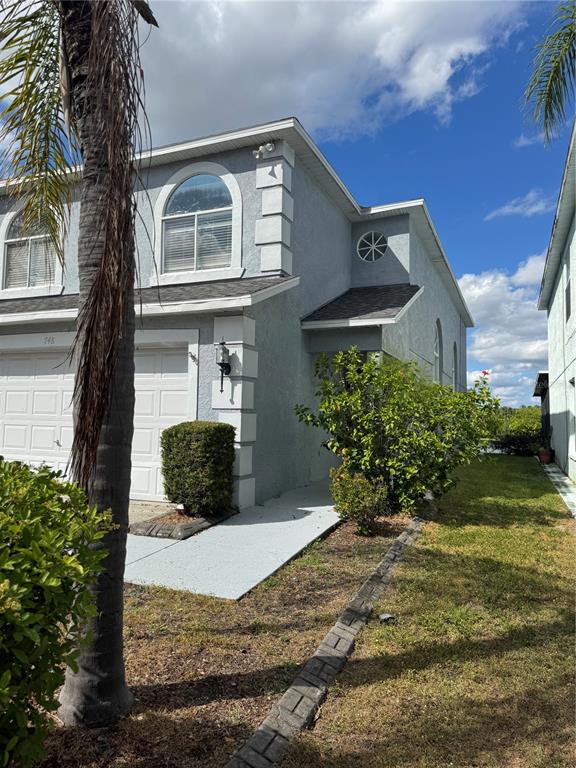 A two-story light gray house with a garage, arched window, and a palm tree — 748 BURLWOOD STREET, BRANDON, FL