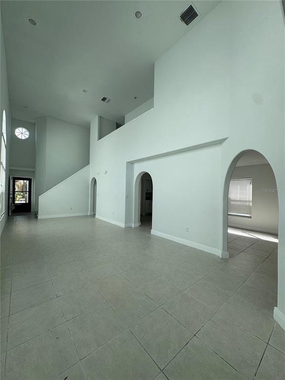 An empty room with high ceilings, tile flooring, and multiple arched doorways — 748 BURLWOOD STREET, BRANDON, FL
