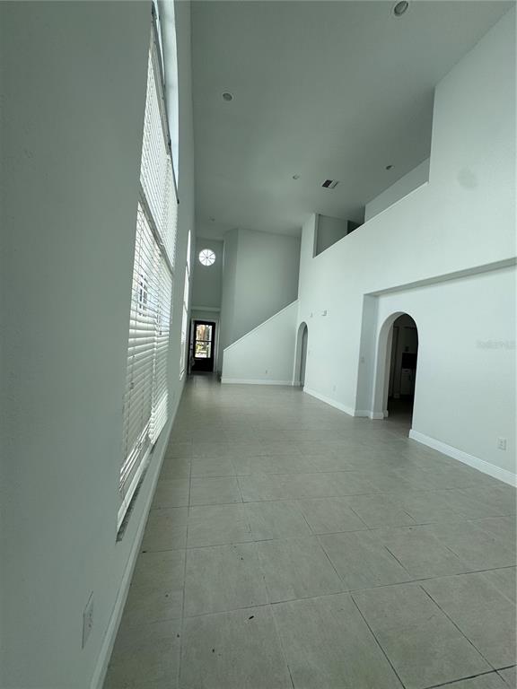 A spacious, high-ceilinged room features light-colored tile flooring, white walls, and large windows — 748 BURLWOOD STREET, BRANDON, FL