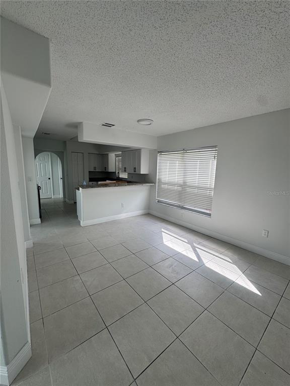 A bright, open-concept living area with light-colored tile flooring and a kitchen with white cabinets — 748 BURLWOOD STREET, BRANDON, FL
