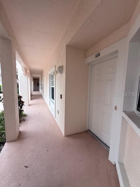A covered outdoor walkway leads to a white front door of a residential unit — 4220 CENTRAL SARASOTA PARKWAY UNIT 1215, SARASOTA, FL
