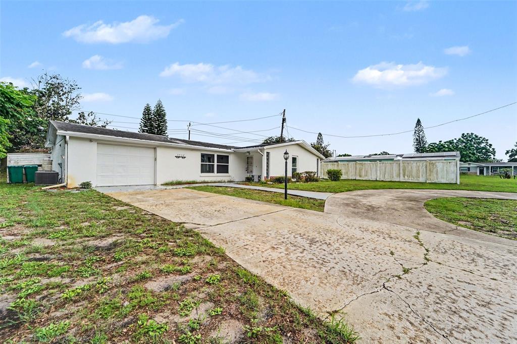 A single-story house with a white exterior, a one-car garage, and a cracked concrete driveway — 3536 KIMBERLY OAKS DRIVE, HOLIDAY, FL