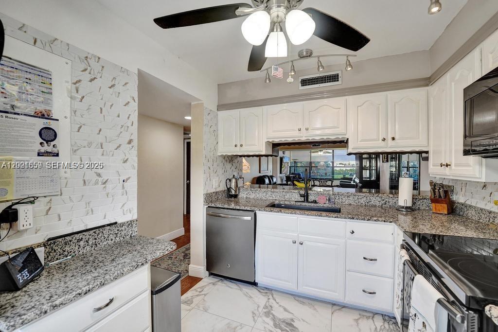A kitchen features white cabinets, granite countertops, stainless steel appliances, and a ceiling fan — 1502 Whitehall Dr # 305, Davie FL 33324, DAVIE, FL