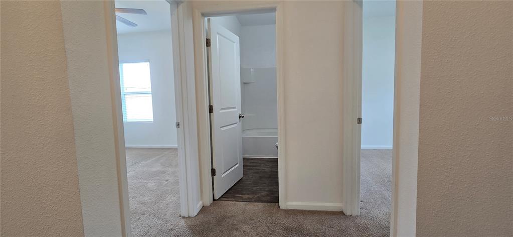 A hallway leads to a bathroom with a tub and two carpeted bedrooms — 15660 MERLIN AVENUE, MASCOTTE, FL