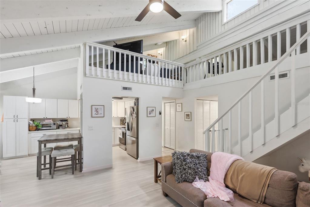 A living room with a vaulted ceiling, a loft, and an open kitchen area — 200 FAIRWAY DRIVE UNIT 200, LONGWOOD, FL